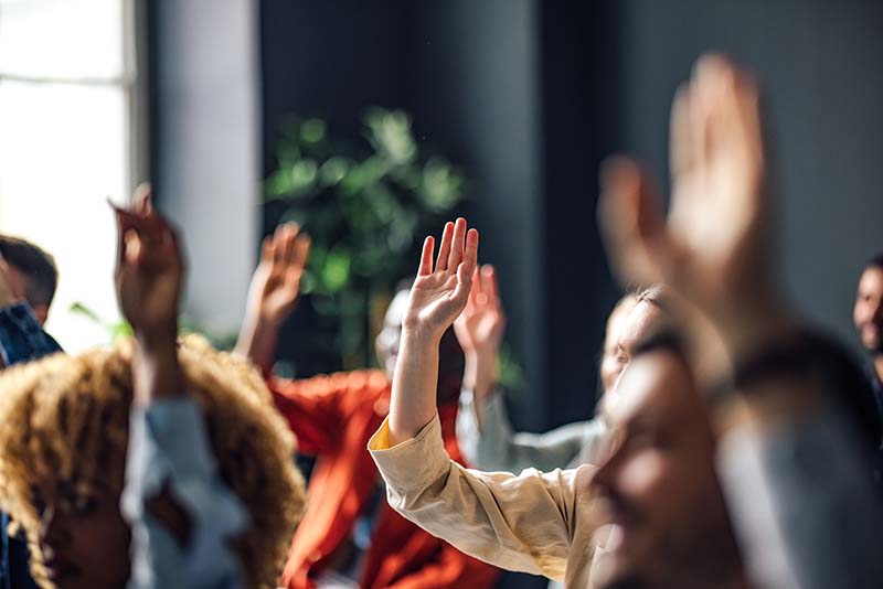 students in classroom raising hands